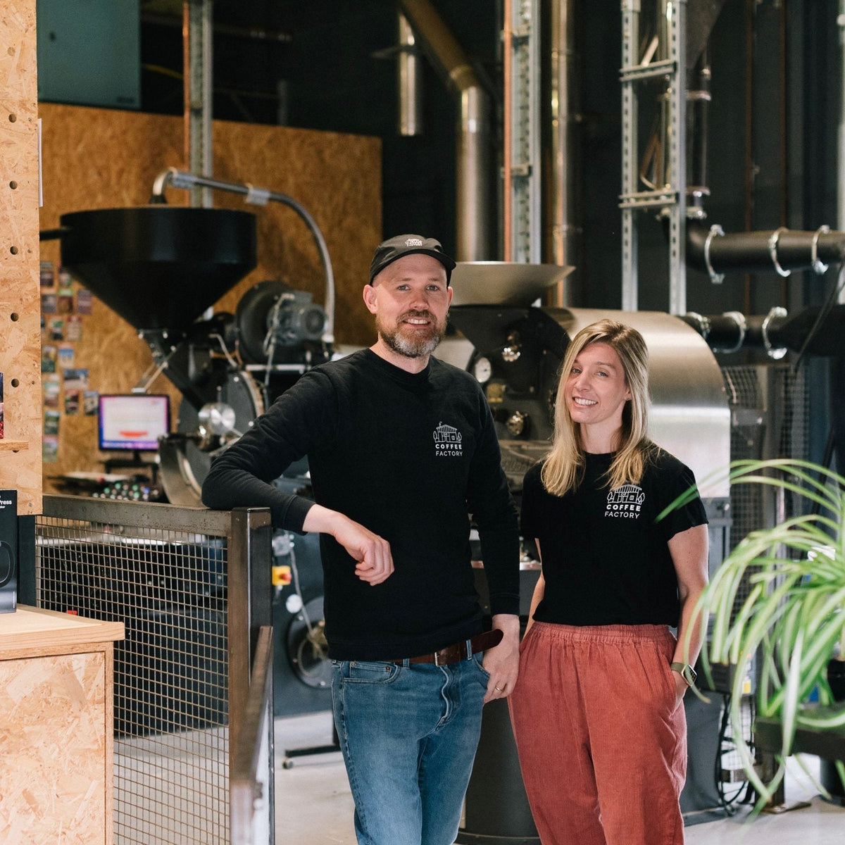 Danny and Justine of Coffee Factory standing in front of their roasters at Seaton Junction